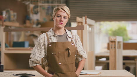 portrait of serious female apprentice working as carpenter in furniture workshop