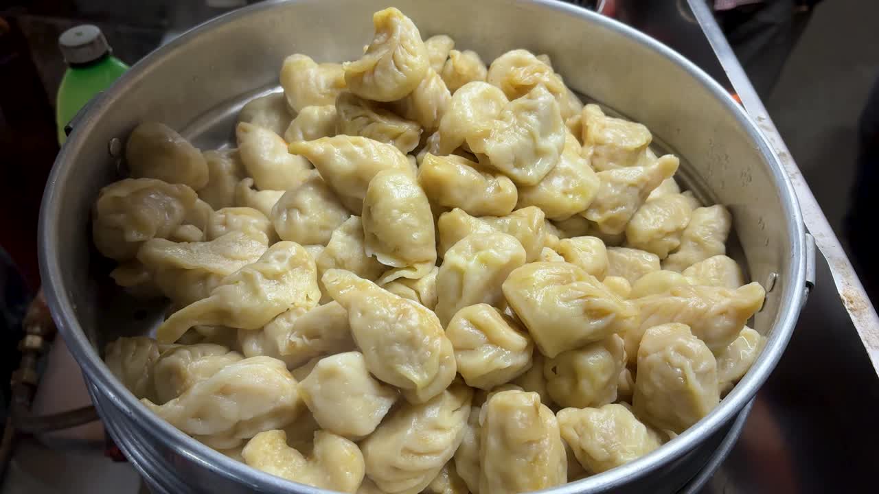 Momos de verduras calientes humeando dentro de un recipiente de acero inoxidable