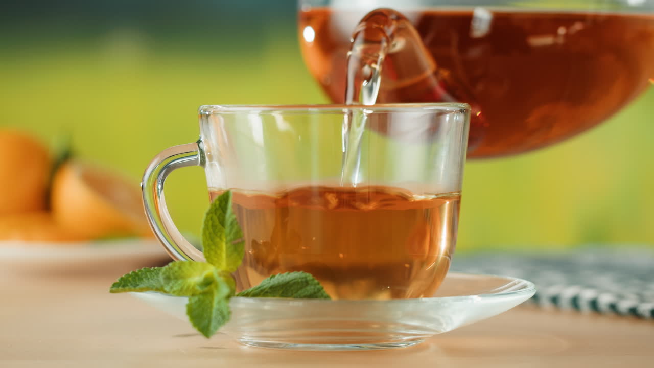 Glass tea cup with fresh mint leaves and hot tea.