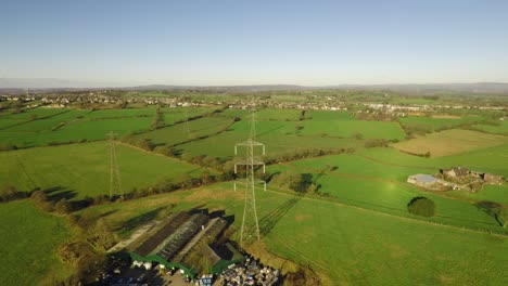 aerial footage of high voltage electricity towers and power lines in the beautiful staffordshire countryside, agricultural fields and farms