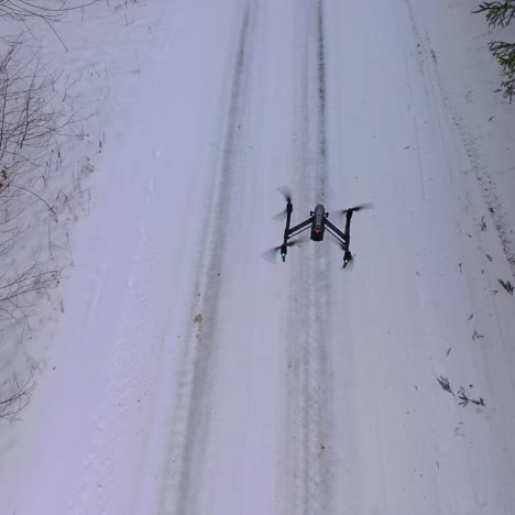 drone flying above forest covered with snow