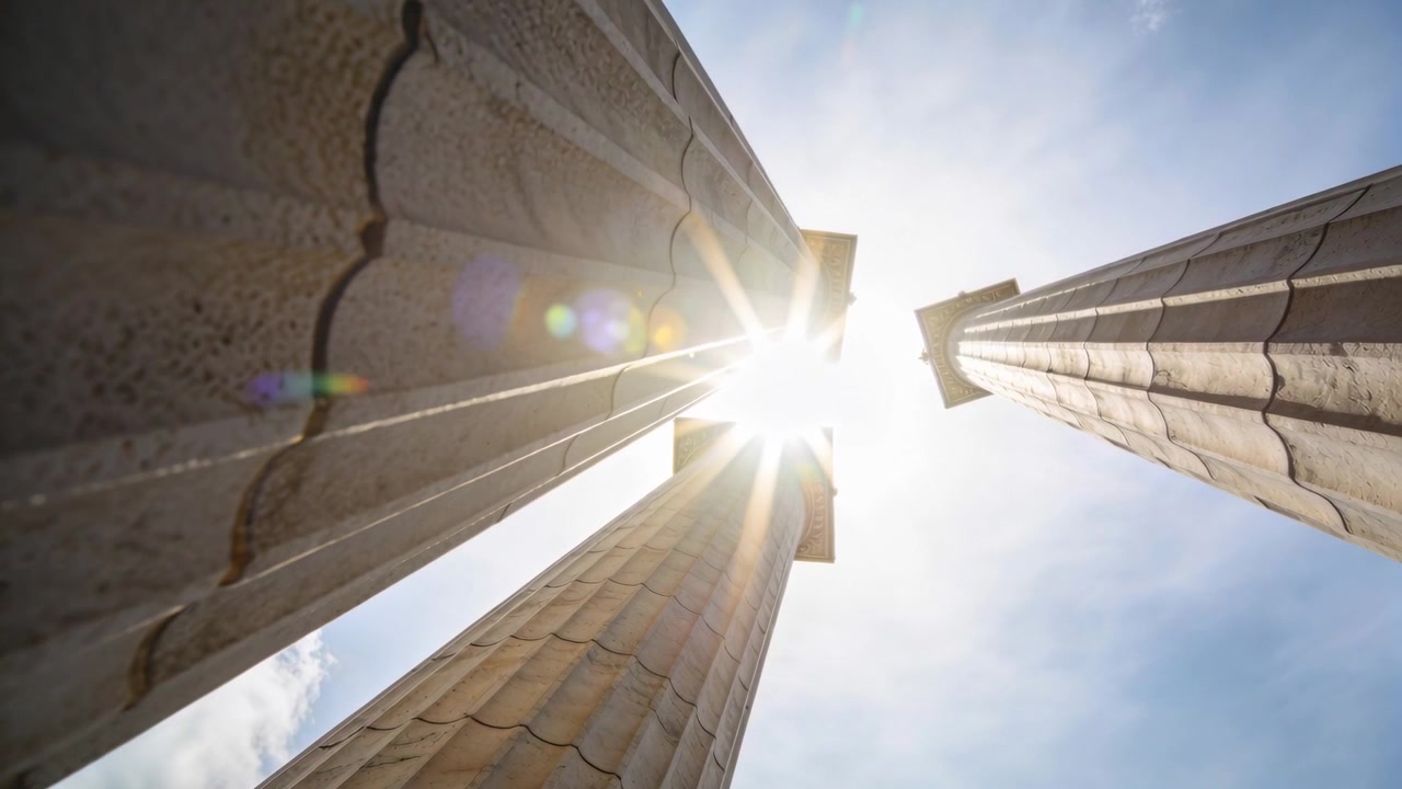 Luce solare mutevole che crea un bagliore sull'obiettivo attraverso tre colonne scanalate, con una leggera inclinazione della fotocamera presso un monumento.
