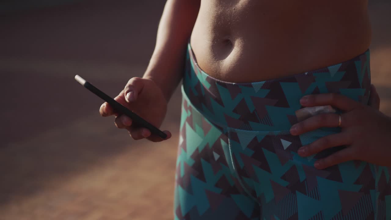 mujer en forma en su teléfono inteligente en un parque