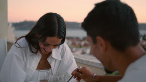 Positive-newlyweds-eating-terrace-with-orange-sunset.-Cheerful-lovers-having-fun