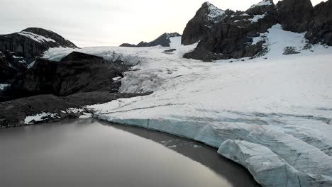 vuelo aéreo sobre el lago glacial de claridenfirn glaciar en uri, suiza al anochecer con el cielo brillante detrás de los picos alpinos y los icebergs flotantes en el agua