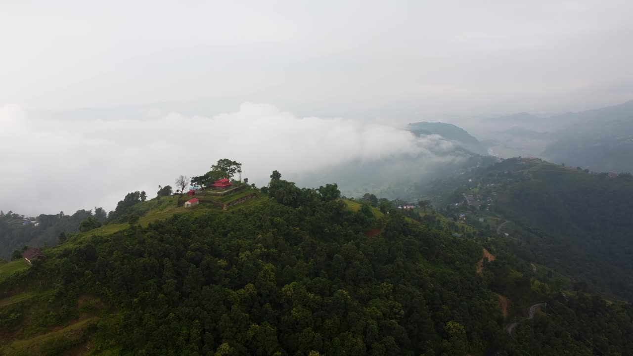 Cinematic drone shot of asian building on toi of green mountain in Nepal - Rainforest hills scenery in background