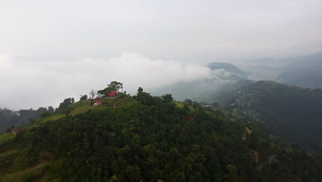 cinematic drone shot of asian building on toi of green mountain in nepal - rainforest hills scenery in background