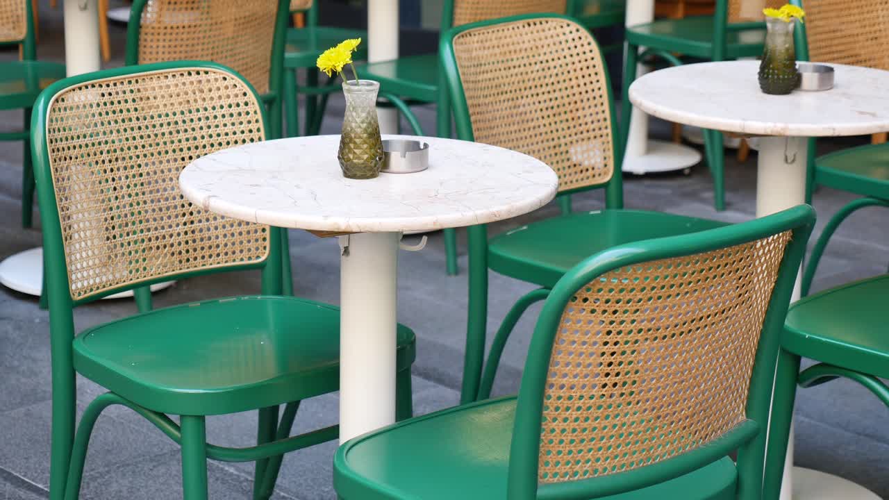 Caffè all'aperto vuoto con sedie verdi e tavoli in marmo.
