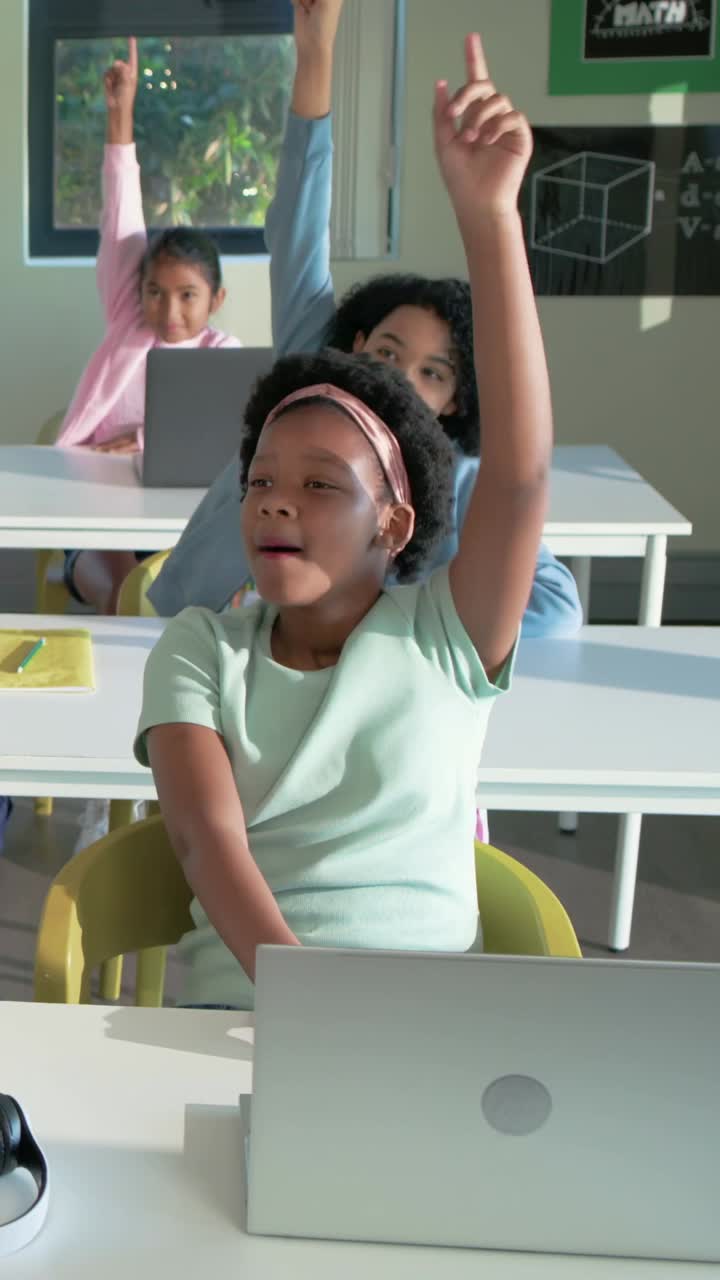 Vertical video: Raising front pupil in class pink headband after prompt, others joining with laptop