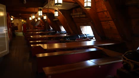 Below-decks-of-old-warship-featuring-cannons-and-hammock