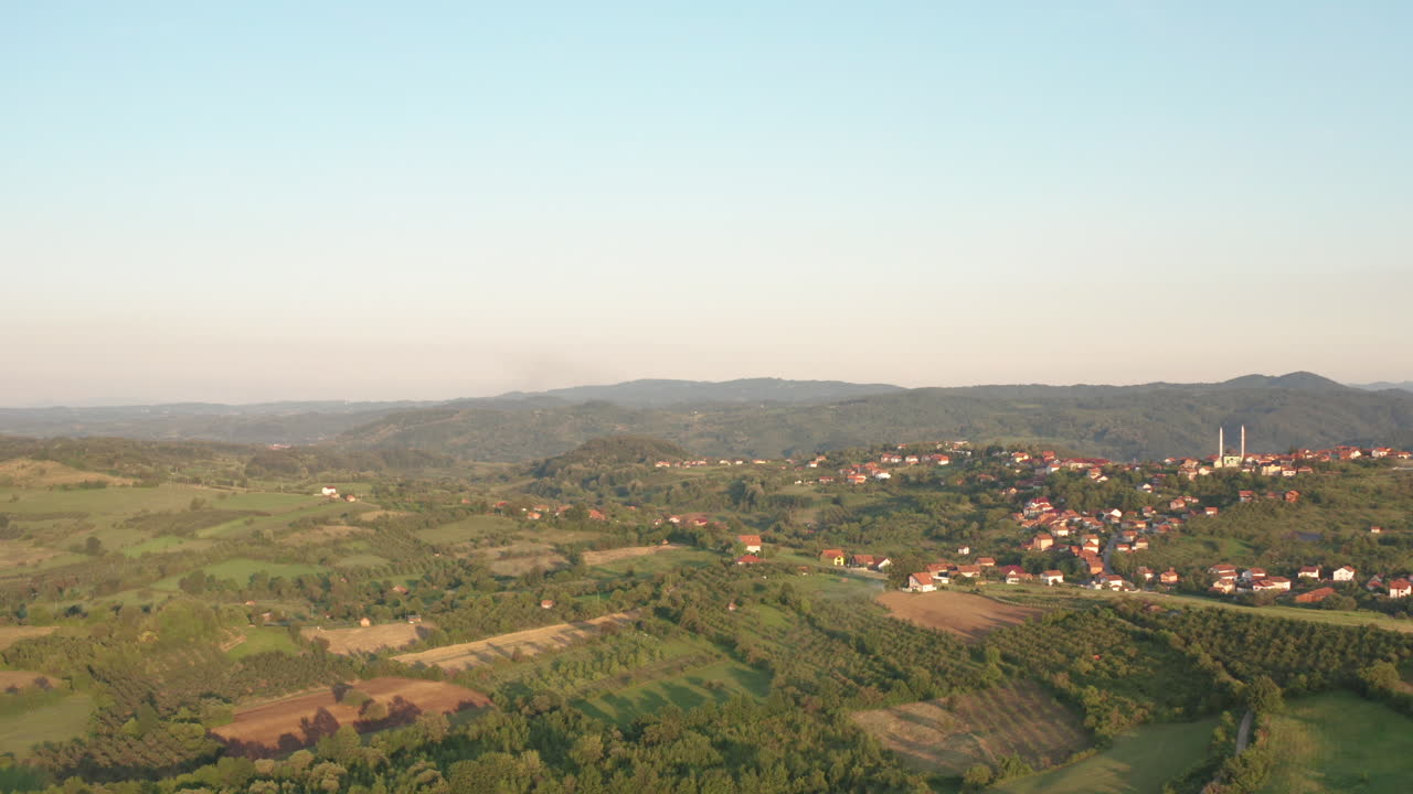 drones cinematográficos sobre montañas con bosque verde y pueblo rural en medio de las montañas
