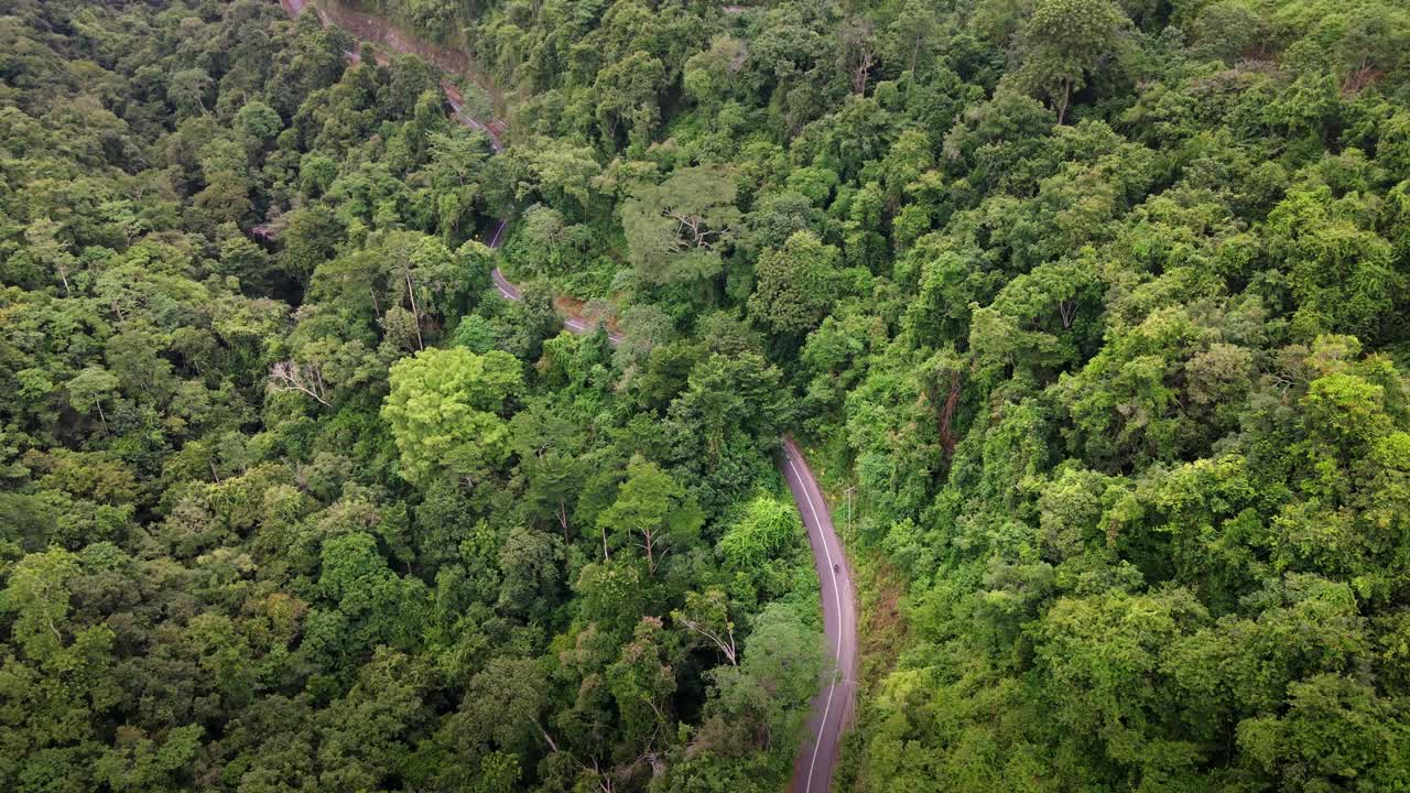 vista aérea de la remota carretera con curvas con motociclistas sobre la cima de la montaña con selva verde en la isla de sumbawa, indonesia