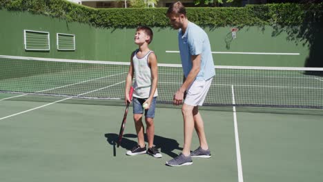 Kaukasischer-Vater-Bringt-Seinem-Sohn-An-Einem-Strahlend-Sonnigen-Tag-Das-Tennisspielen-Auf-Dem-Tennisplatz-Bei