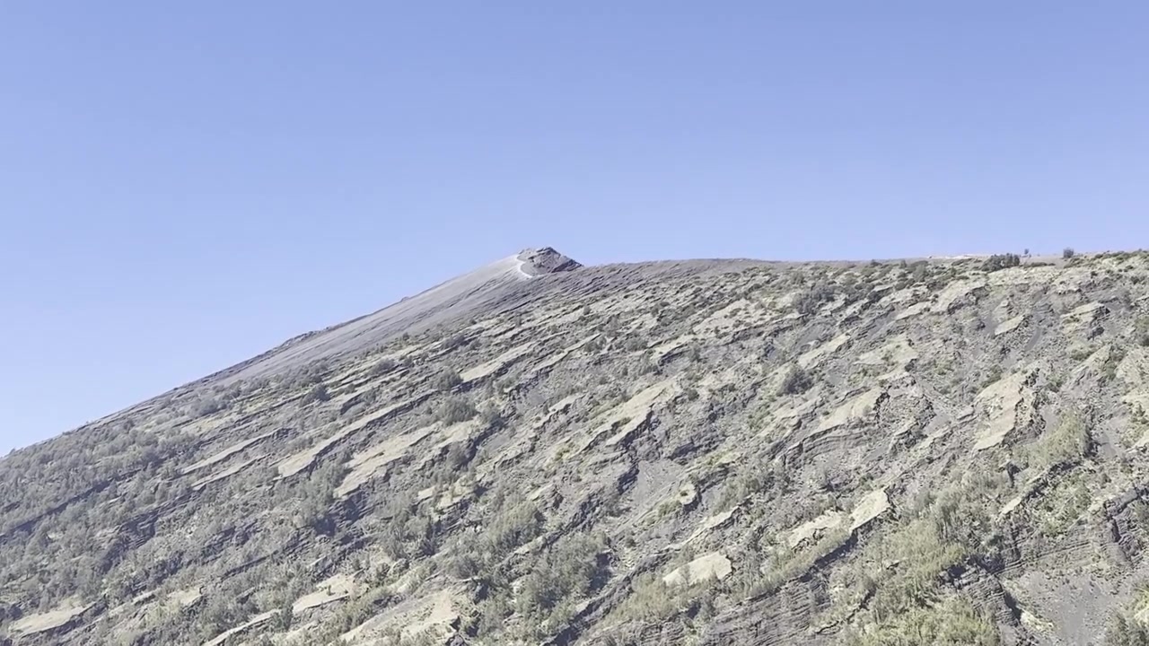 Paesaggio vulcanico con fumo che sale dal cratere.