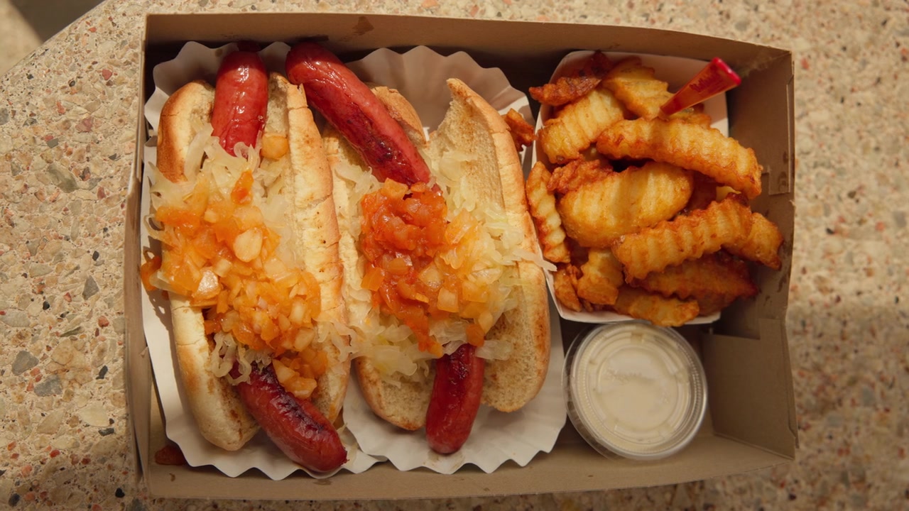 Hot dog kentang goreng keriting, bawang bombay cincang, saus mayones ranch di Nathan's di Coney Island, AS