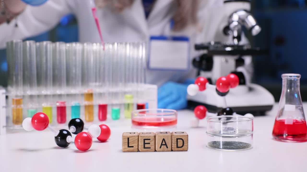 Scientist conducting an experiment in a laboratory with various scientific instruments and the word "LEAD" spelled out