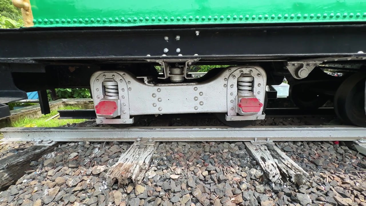 Ripresa grandangolare in movimento del gruppo sospensione e del binario ferroviario sotto una locomotiva a vapore conservata. Solo per uso editoriale