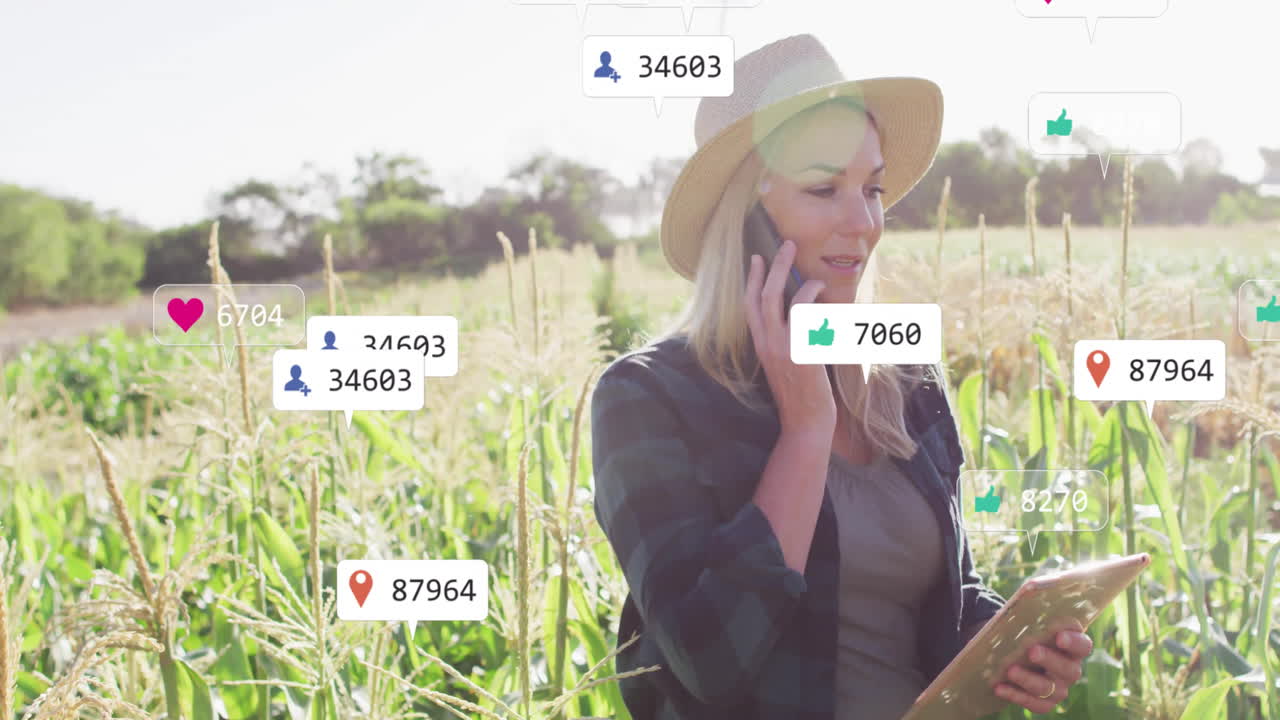 Woman using phone and tablet while tracking social media data in cornfield, showing floating icons