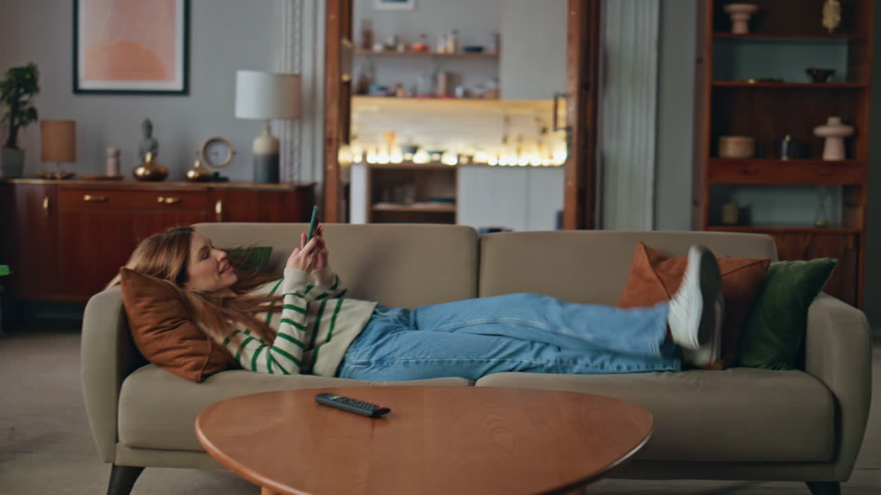 Carefree girl lying couch living room with cellphone. Woman making selfie phone