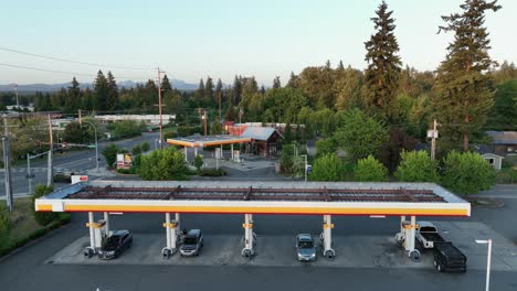 Drone-shot-pulling-away-from-cars-filling-up-at-a-gas-station