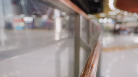 a blurred view of a skiing area with people skiing in the background. highlighting the polished handrail and active environment of the skiing area