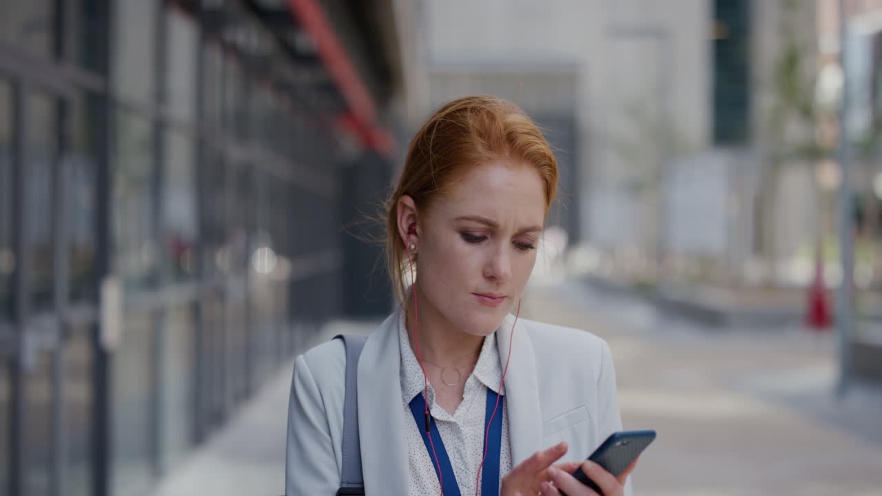 портрет профессиональной молодой деловой женщины, использующей смартфон, отправляющей текстовые сообщения, наслаждающейся прослушиванием музыки, носящей наушники в расслабленном городском замедленном движении