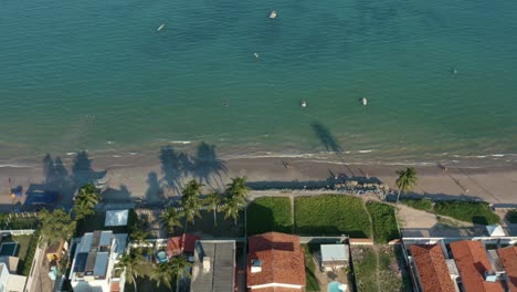 truck left aerial drone shot of the tropical bessa beach in the capital city of joao pessoa, paraiba, brazil with people enjoying the ocean surrounded by palm trees, beach houses, and fishing boats