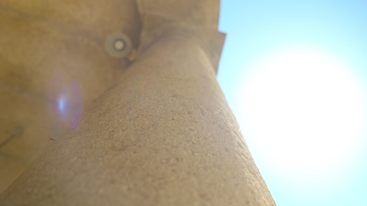 contra el telón de fondo del cielo azul y el sol brillante, hay una estructura de piedra