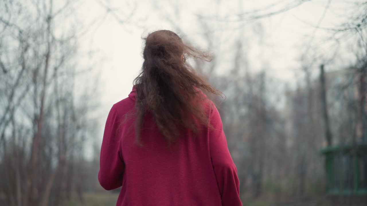 Leisurely Woman With Ponytail In Winter Woods, Runner In Hooded Clothing Navigates Leafless Forest During Cold Weather, Woman In Hoodie Jogs Through Wintery Woods As Cold Surrounds Her