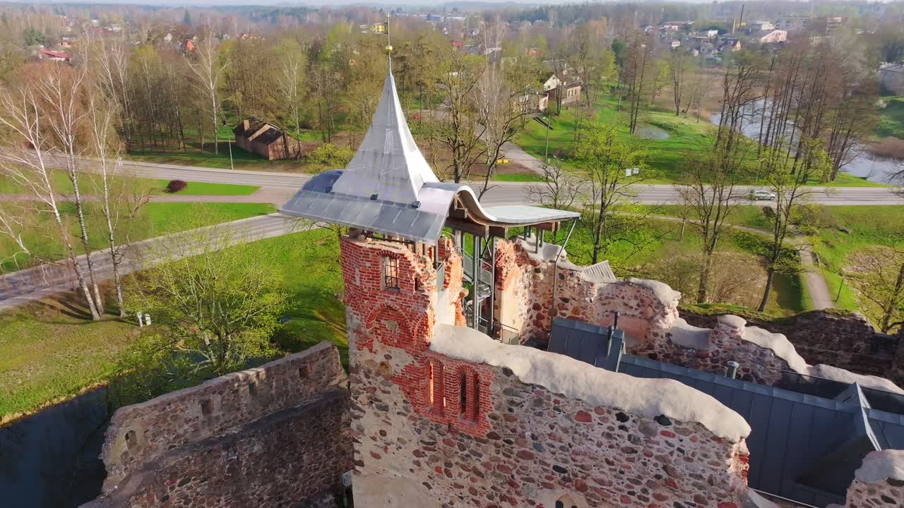 Ancient castle tower orbit reveals Dobele town and river bridge in spring light