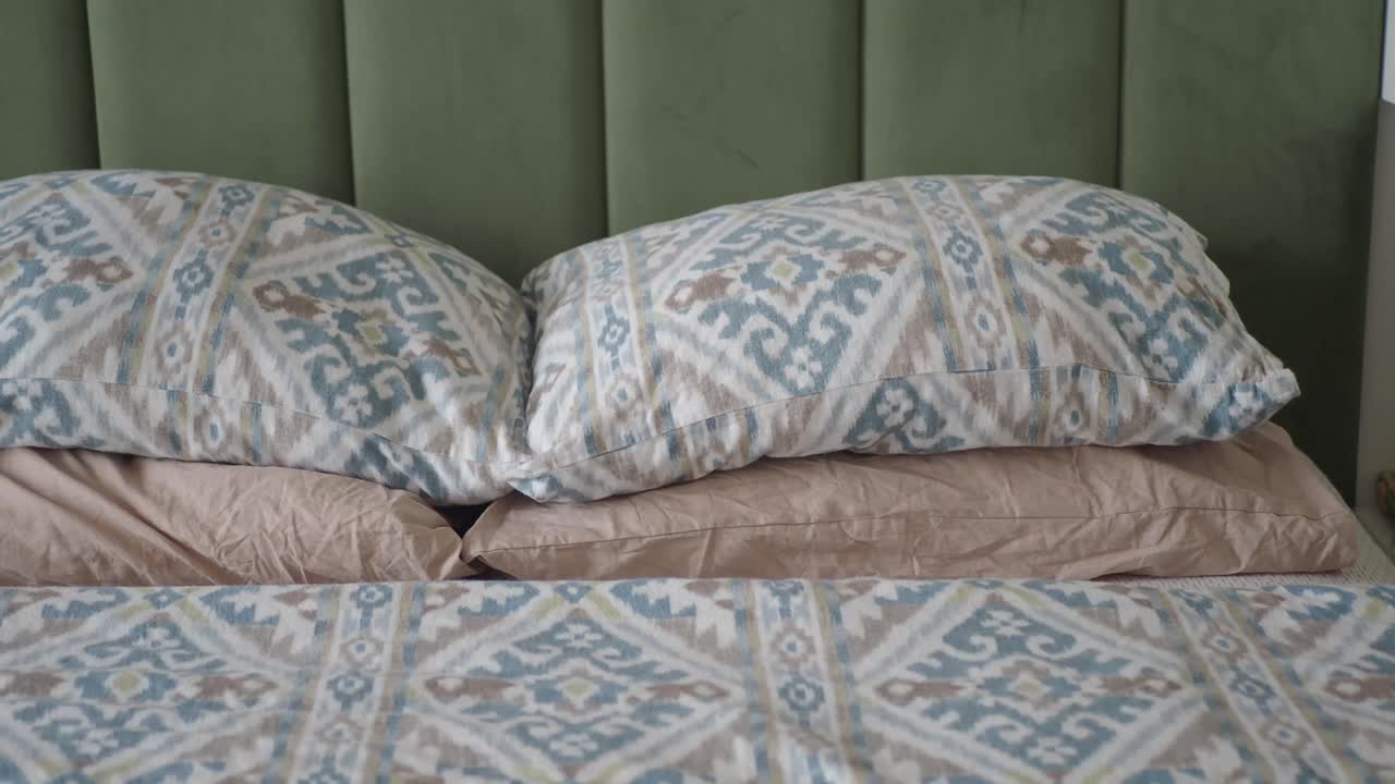 Comodo letto con cuscini a fantasia e testiera imbottita verde