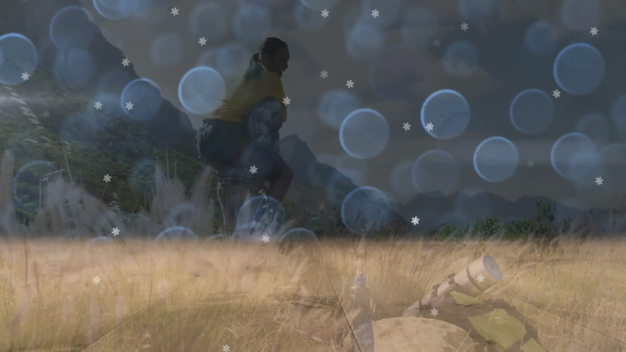Hiking couple exploring golden grass field, with camping backpack and snowflake overlays for travel