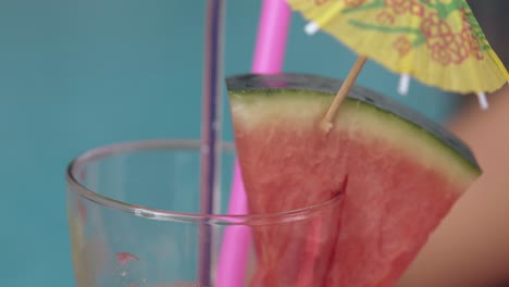 girl-holds-glass-with-yellow-drink-umbrella-in-watermelon