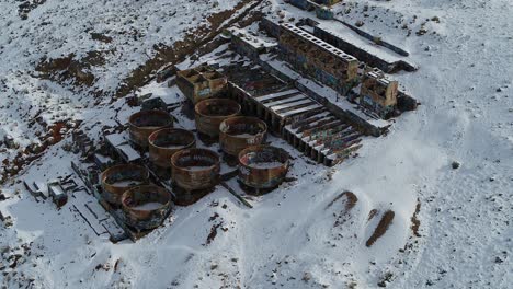 a drone orbits the rusty old tintic mill in geneloa, utah, revealing the decaying water tanks, leaching tanks, roasters and crusher built in 1920