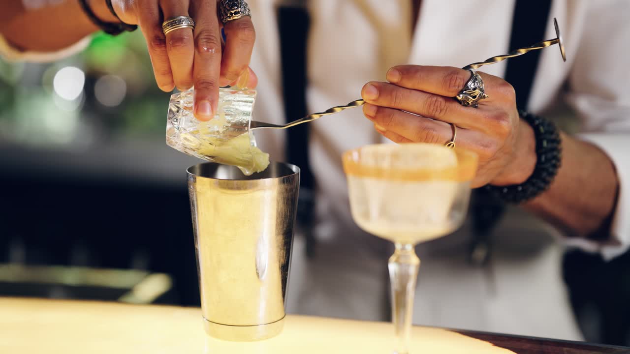 Barman che versa ingredienti per cocktail in uno shaker al bar