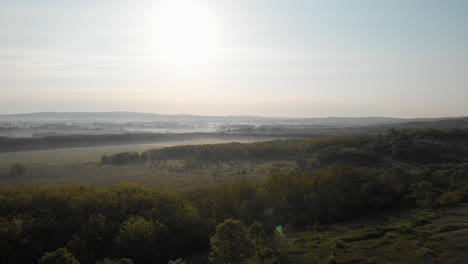 aerial pullback establishing view of a foggy field with nature landscape, morning