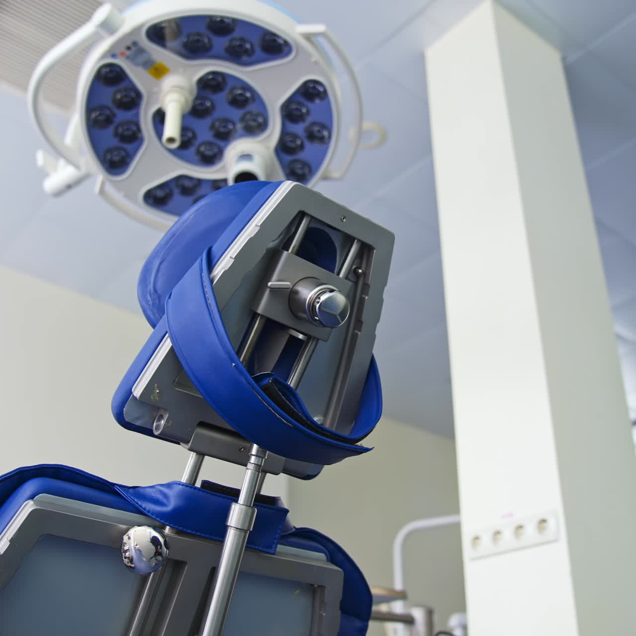 Folding chair with different appliances standing under the powerful lamp in dentist's cabinet. Close up. Low angle view. Blurred backdrop