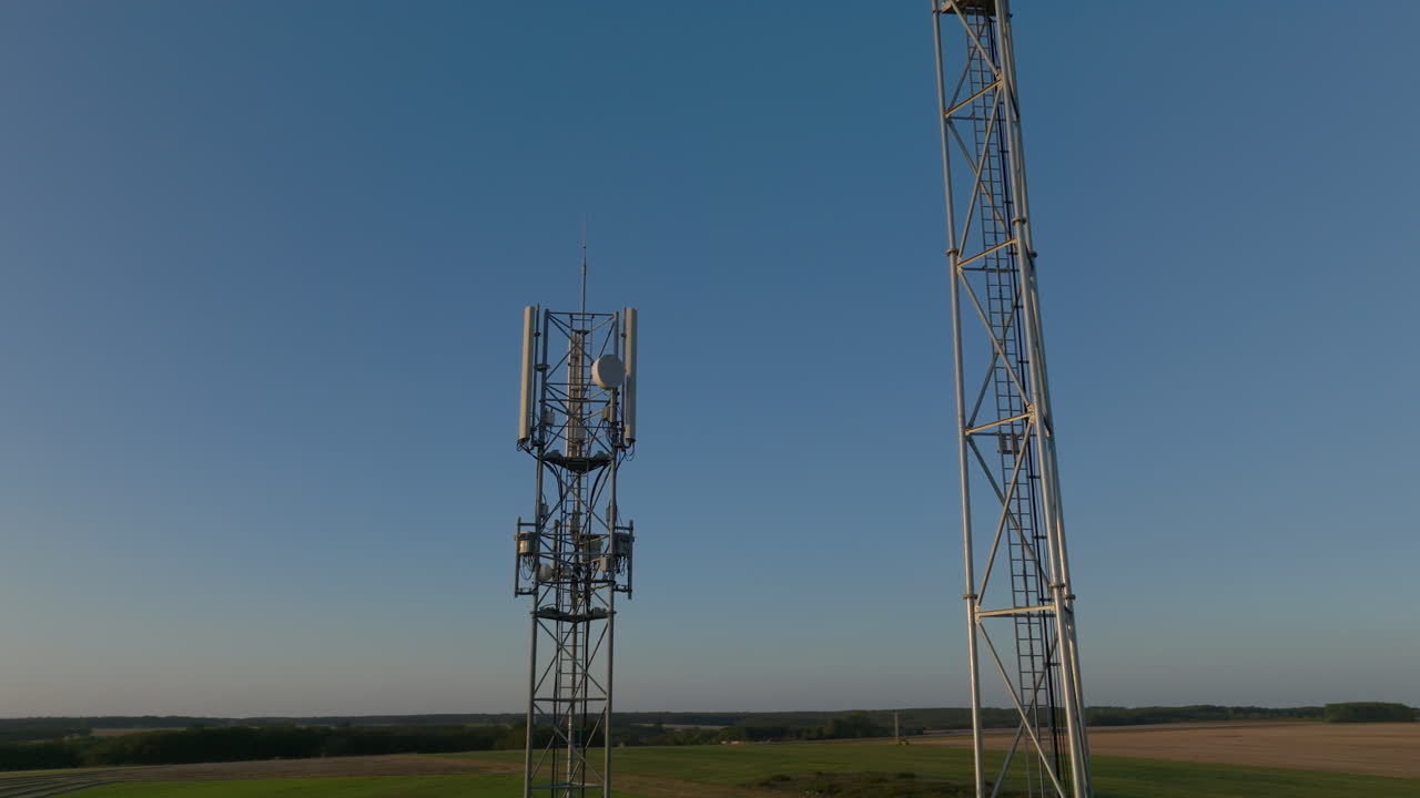 dos torres celulares en el medio de tierras de cultivo con fondo del cielo, primer plano orbital aéreo