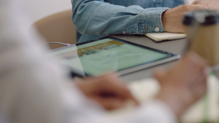 business woman hands writing taking notes in corporate meeting colleague using tablet browsing online close up