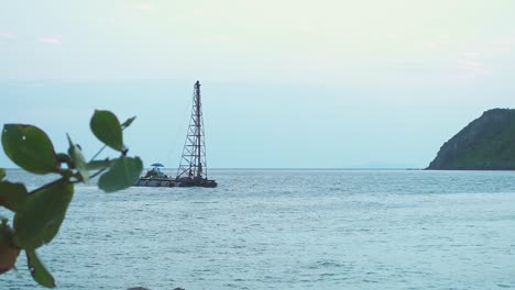 Eine-Kleine-Mini-Bohrplattform-Driftet-Bei-Sonnenuntergang-Ins-Meer