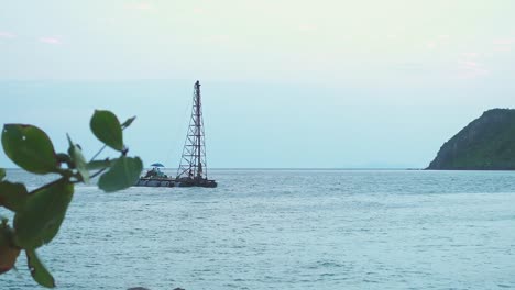 small mini drill platform drifts into the sea in sunset time