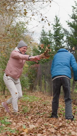 joven y su hermano jugando lanzando hojas secas de otoño el uno al otro al aire libre, con el niño esquivando mientras las hojas rocían a su alrededor en un momento alegre de risa y diversión