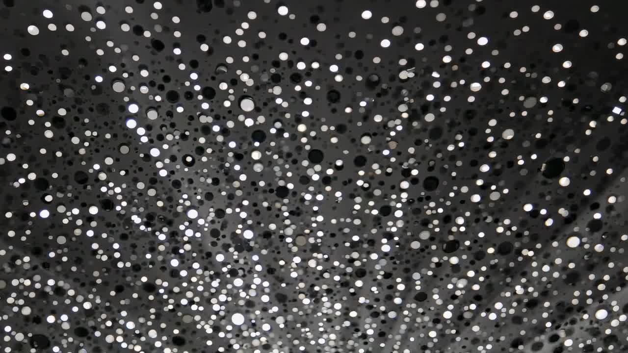 Campo luccicante di cerchi luminosi e vuoti scuri che fluttuano con un lento spostamento di luce su una superficie ravvicinata
