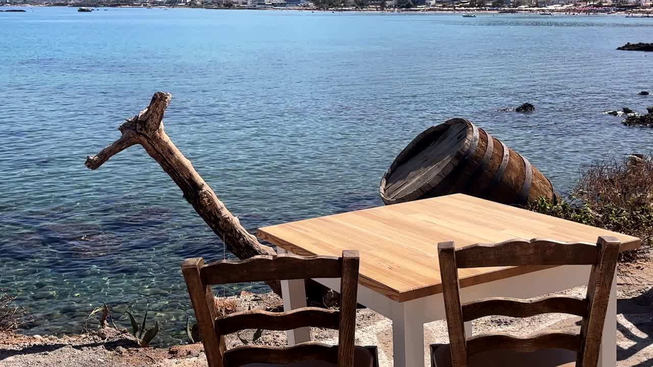 Rustic taverna table and chairs by the sea with barrel, Chersonissos, Crete, Greece
