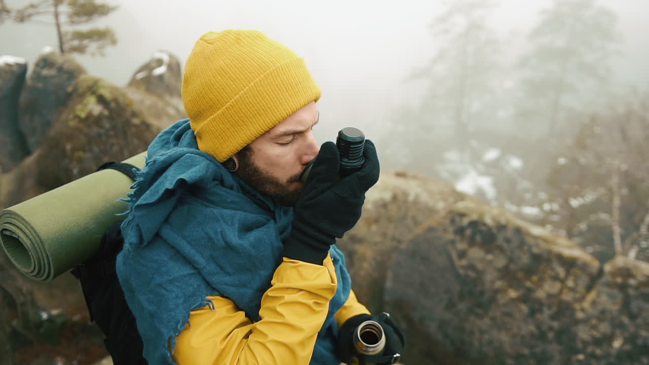 Man drinking hot beverage in foggy mountains
