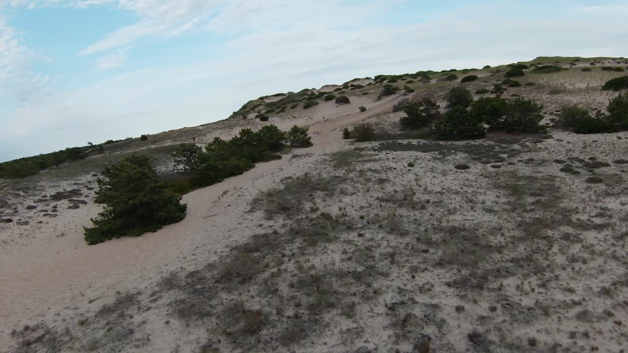 toma de drones fpv de los asombrosos senderos estériles del desierto, dunas de arena, rocas y laderas empinadas con un pequeño follaje tupido ubicado en el sendero dune shacks en la provincia de cape cod, massachusetts