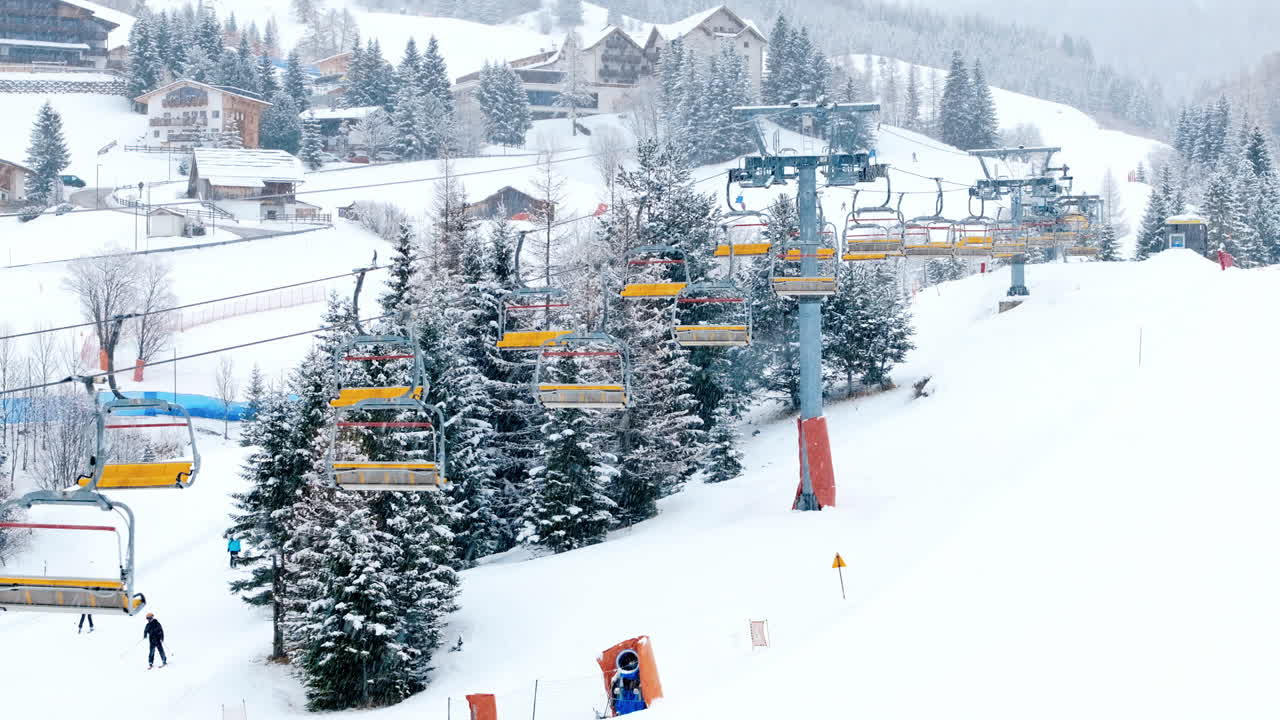 Aerial drone view of a ski lift in Corvara in Badia covered in snow, in South Tyrol, the Dolomites