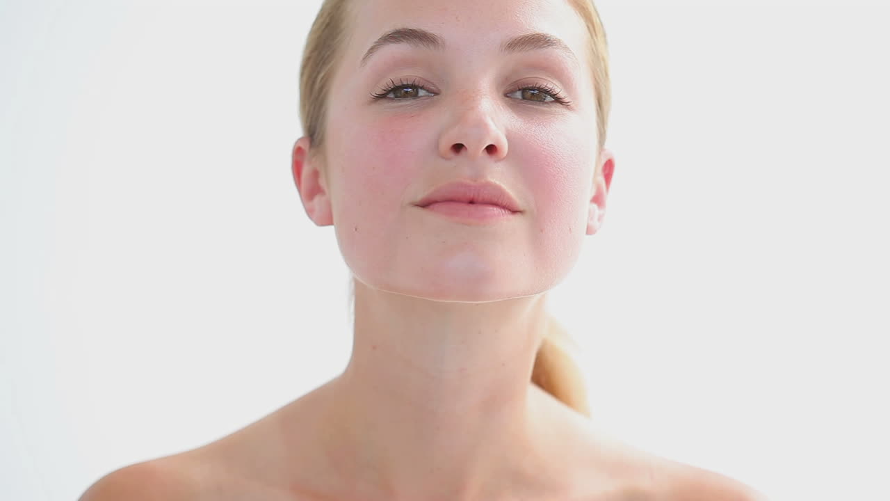 una mujer rubia masajeando sus mejillas.