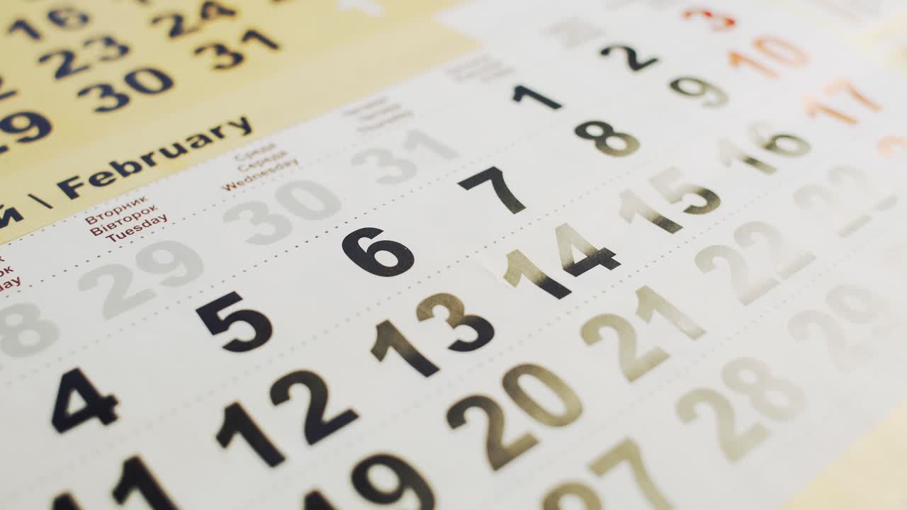 Man's hand lays out red paper heart on the 14 February month in a calendar. Love holiday for young and old