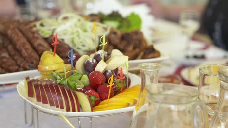 plato de frutas frescas en la mesa de la cena festiva. horquillas de frutas en rodajas variadas